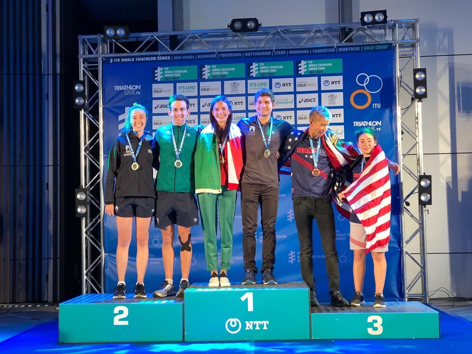 Fátima Alanís on the top step of the 2018 ITU Triathlon World Championship podium in Gold Coast, draped in the Mexican flag with her gold medal.